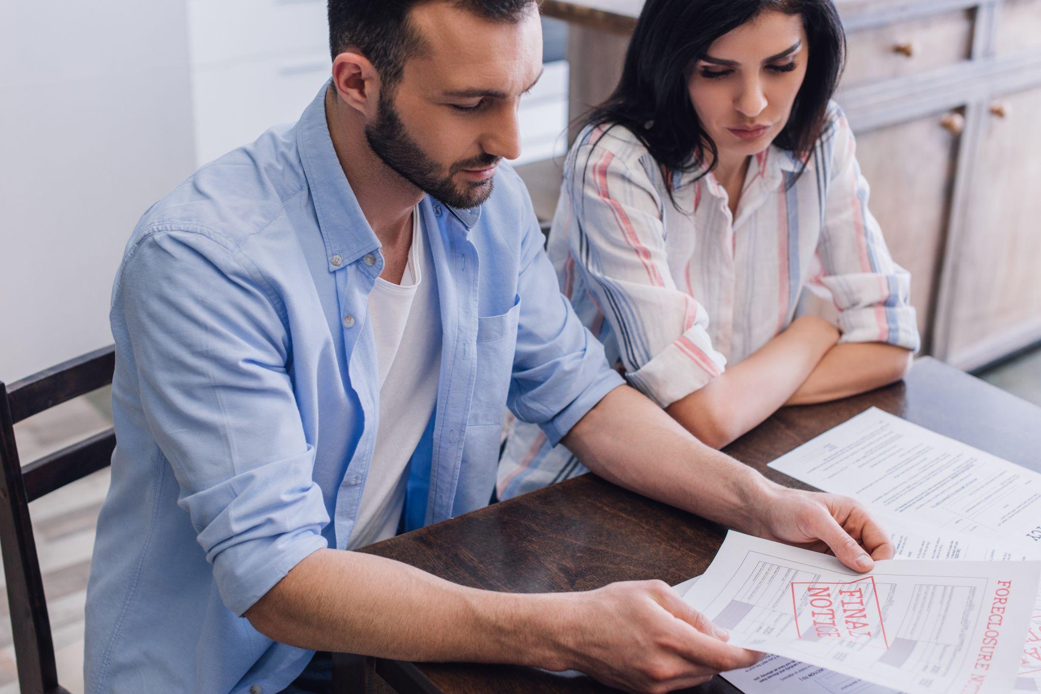 Man reading document with foreclosure and final notice lettering near woman