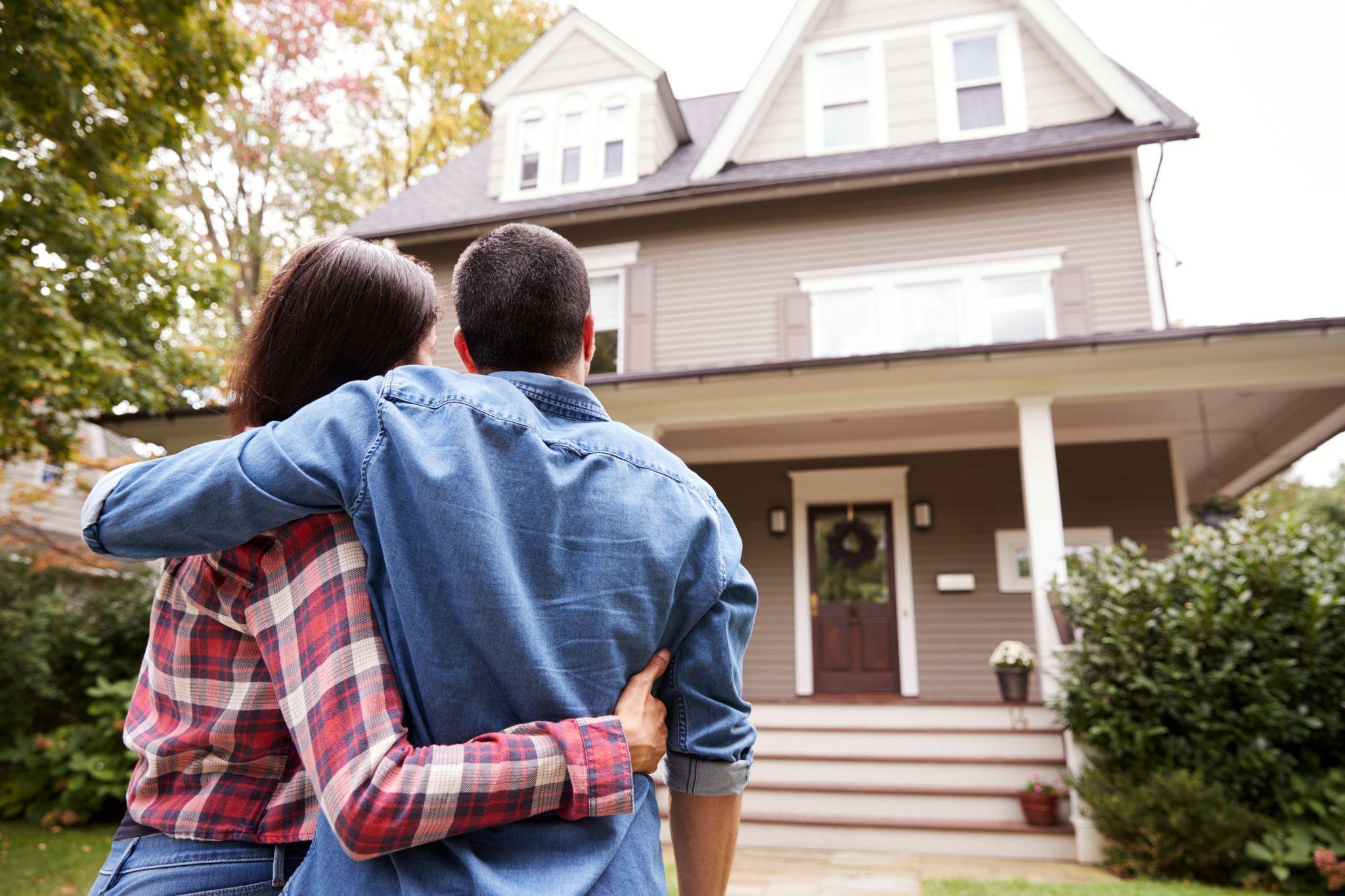 Rear view of loving couple looking at house