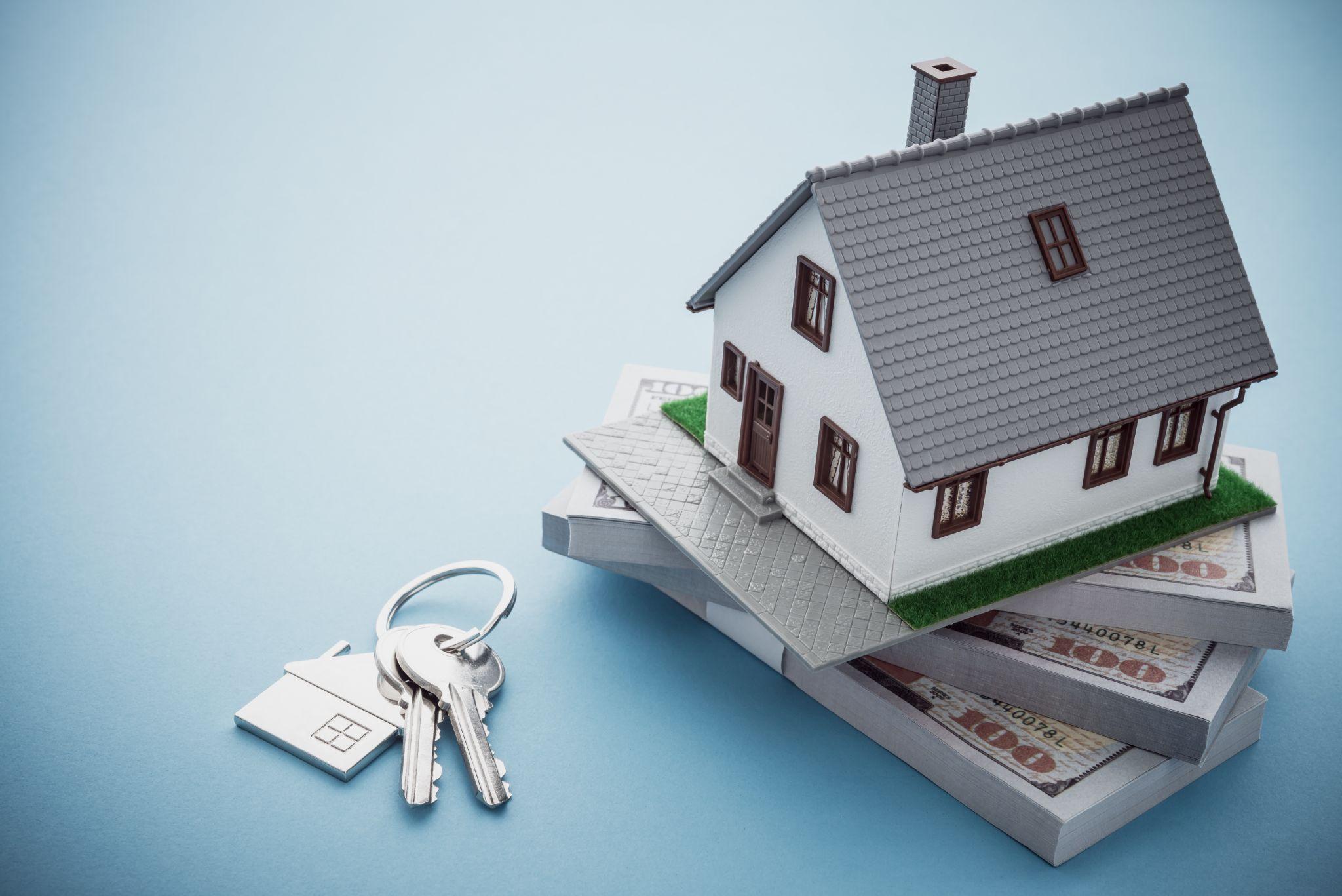 House model, dollar banknotes and key on blue background