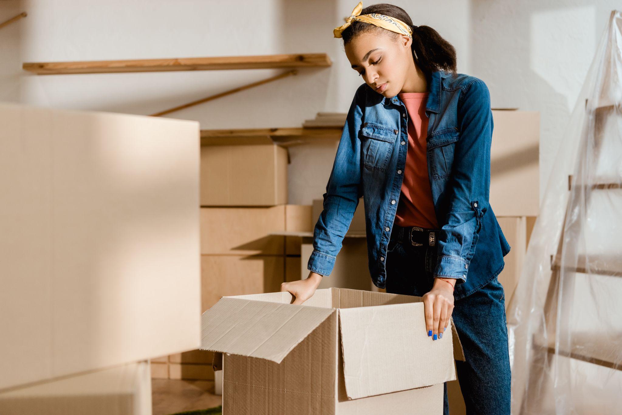 African american girl unpacking cardboard boxes in new apartment