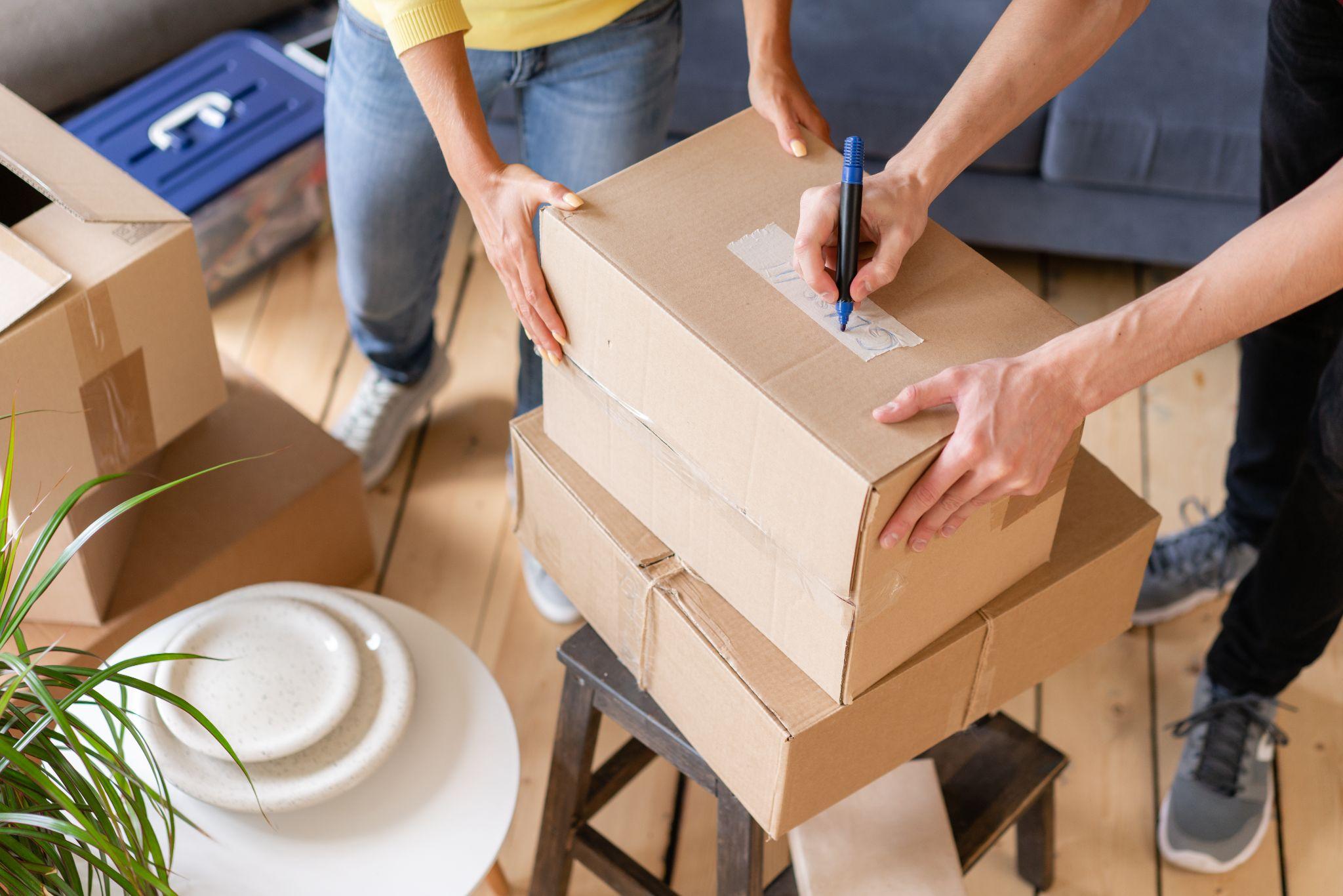 Close up of hand packing cardboard box, concept moving house.