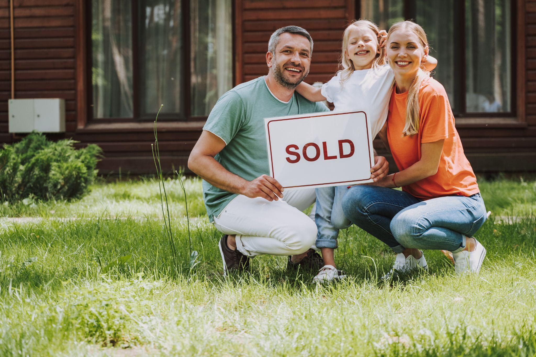 Happy family holding sold card and smiling