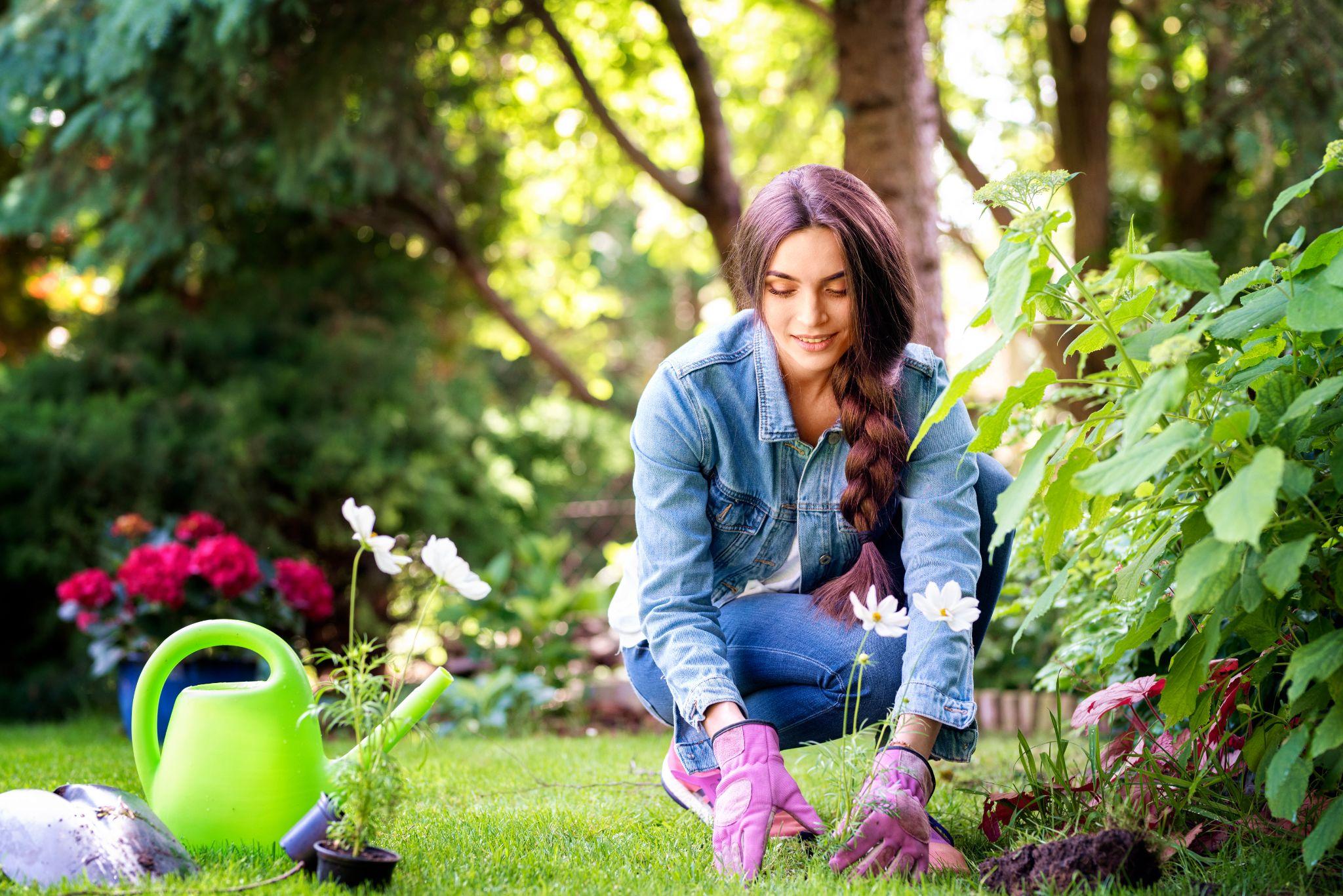 Happy young woman planting flowers in the garden