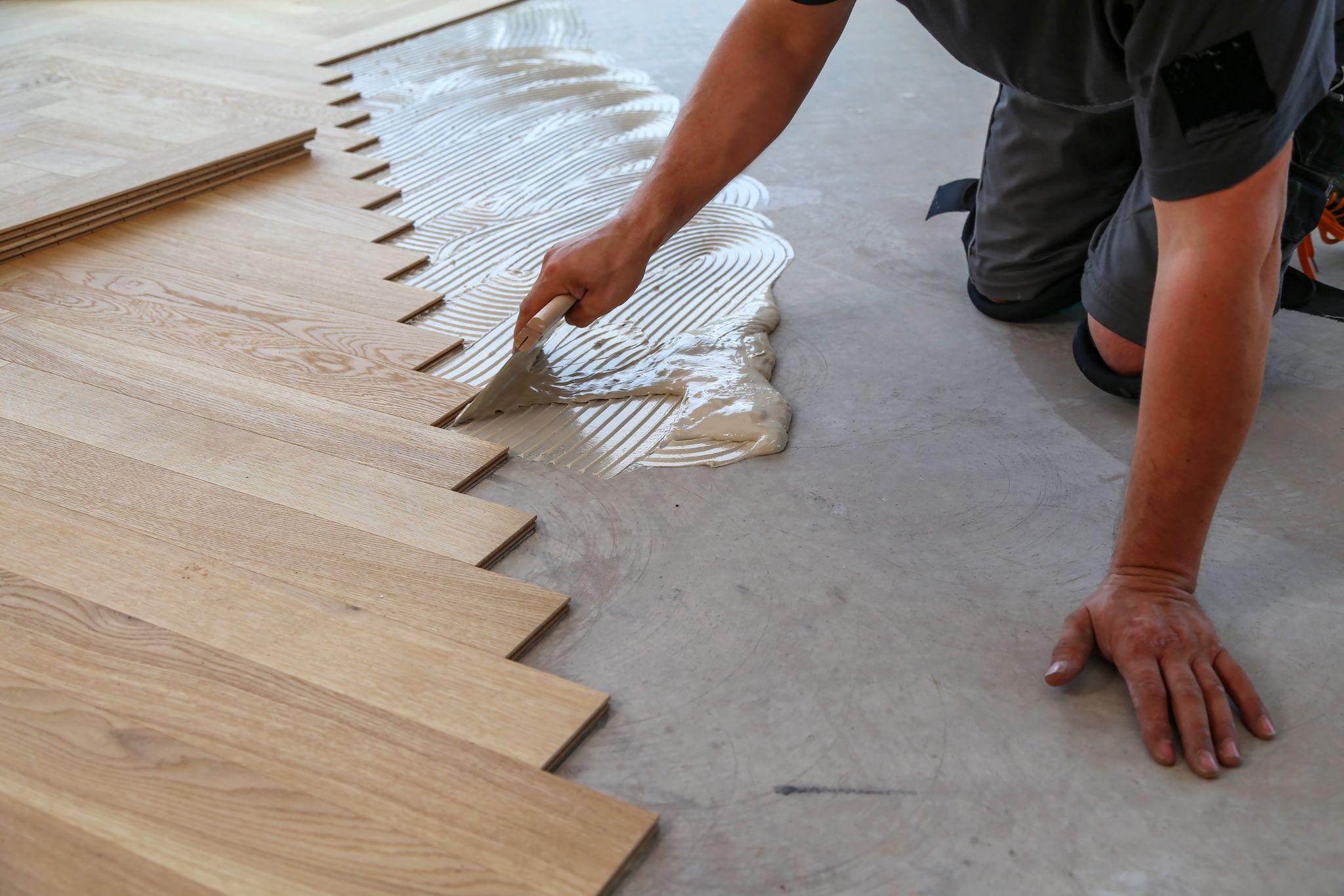 Worker laying parquet flooring.