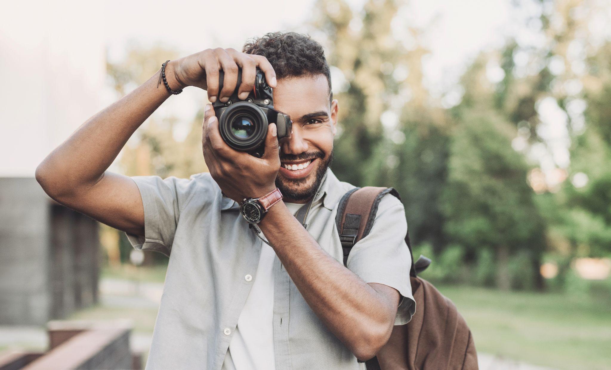 Young man photographer takes photographs with dslr camera in a city