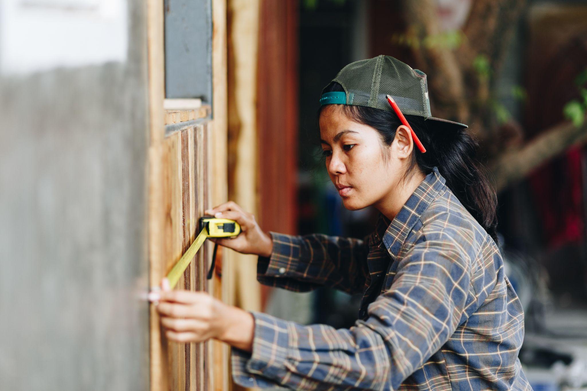 young woman using measuring tape and marking the wall